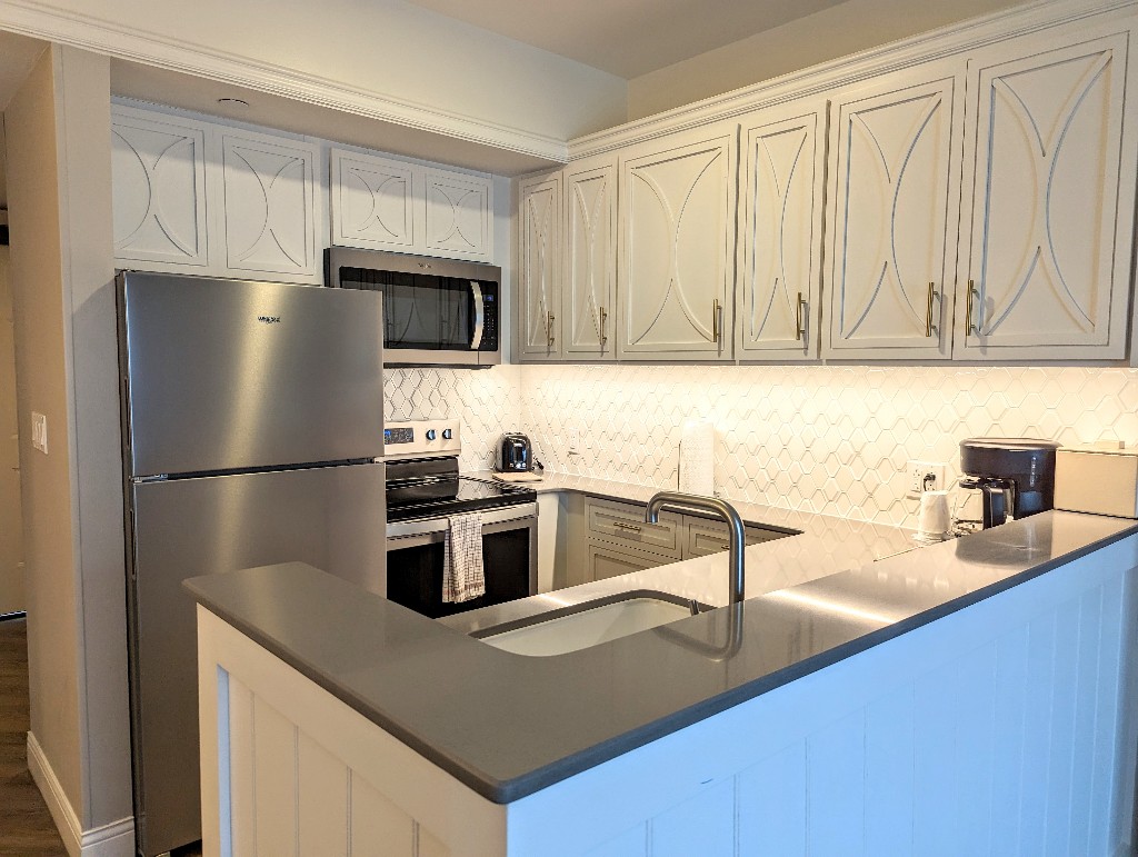 Crisp white cabinets, gray counters, and gold accents make this fully stocked kitchen stylish and functional