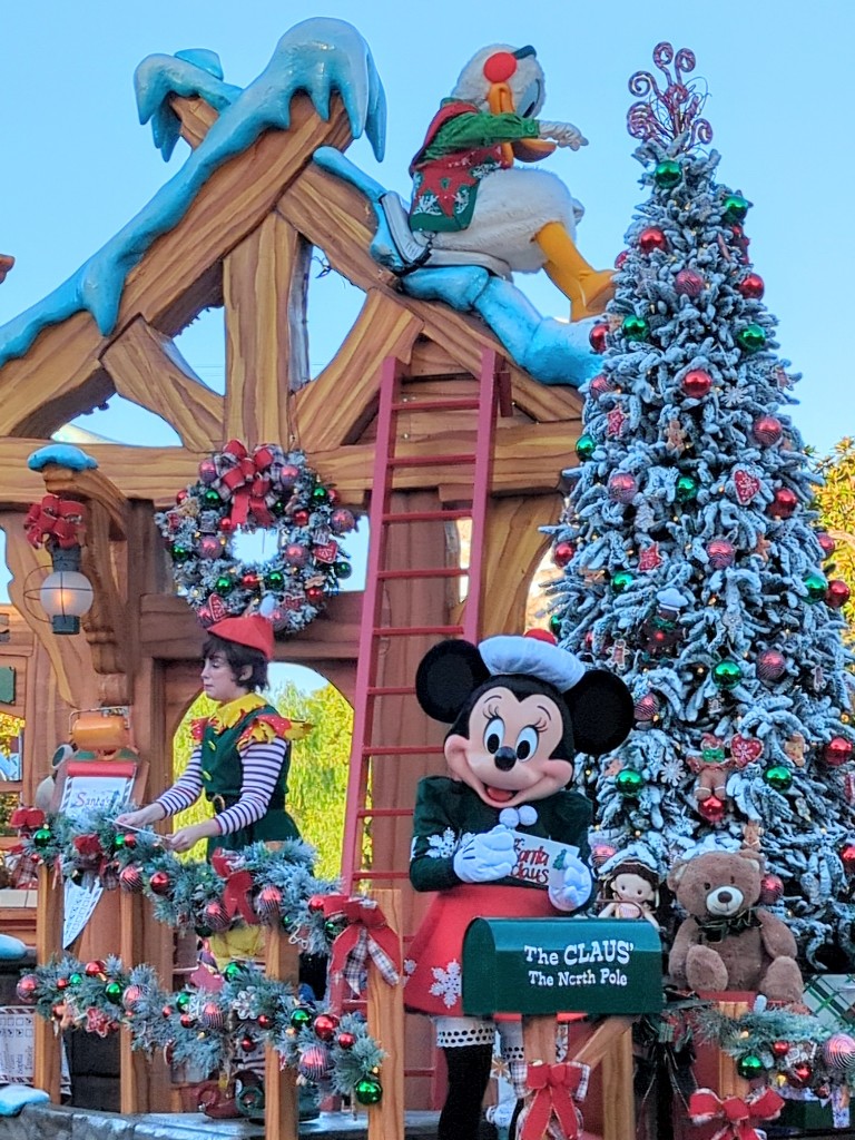 Minnie holds a letter to Santa in front of a flocked tree during A Christmas Fantasy Parade