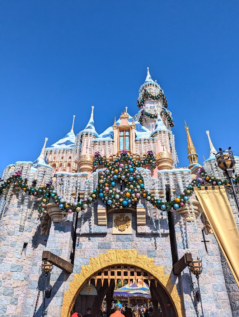 Sleeping Beauty Castle covered in greenery, colorful globe ornaments