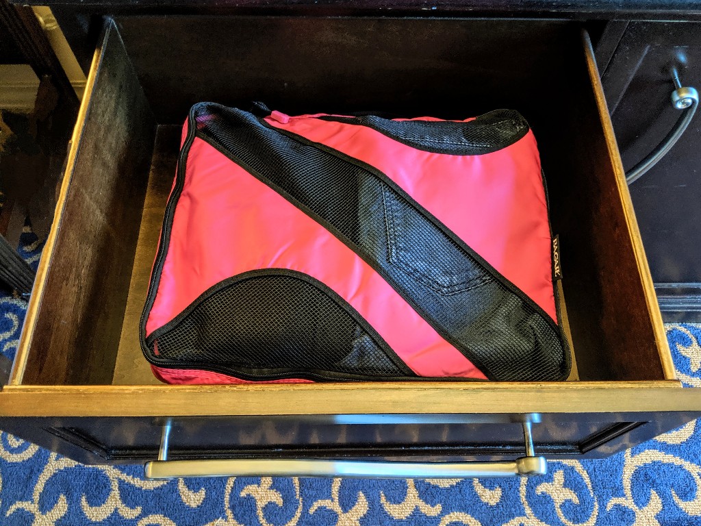 A bright pink packing cube fits neatly into a Disney World resort drawer