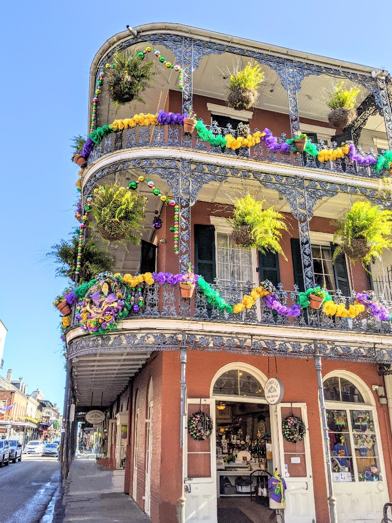 Mardi Gras decorations in gold, green, and purple adorn beautiful iron railings on an iconic French Quarter building