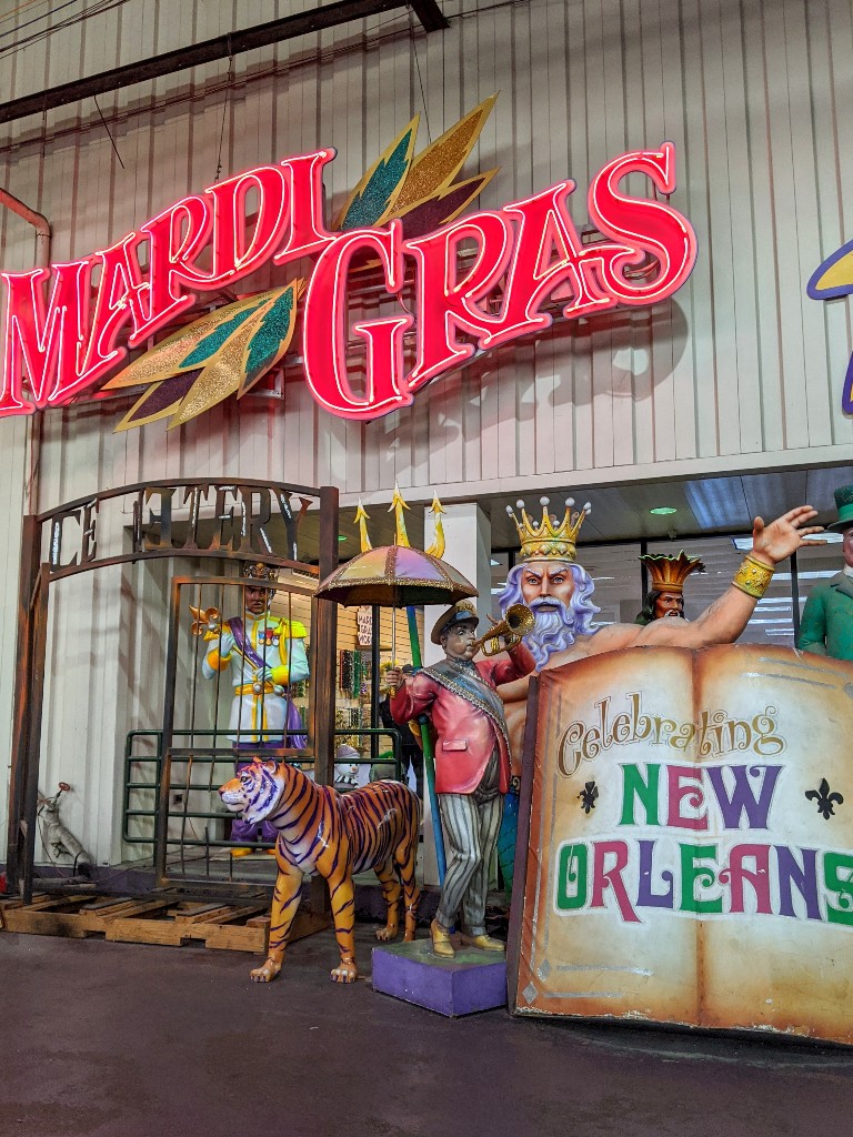 Neon lights spelling out Mardi Gras and several large float decorations welcome guests to Mardi Gras World in New Orleans