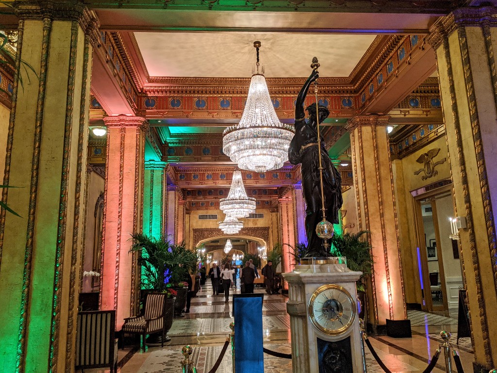 Elegant chandeliers hang above the ornately decorated lobby of The Roosevelt New Orleans