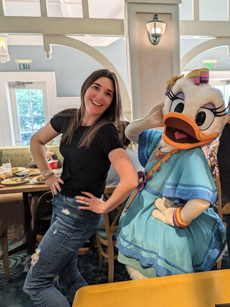 A woman and Daisy Duck do a silly pose with hands on their hips at Cape May Cafe Minnie's Beach Bash Breakfast