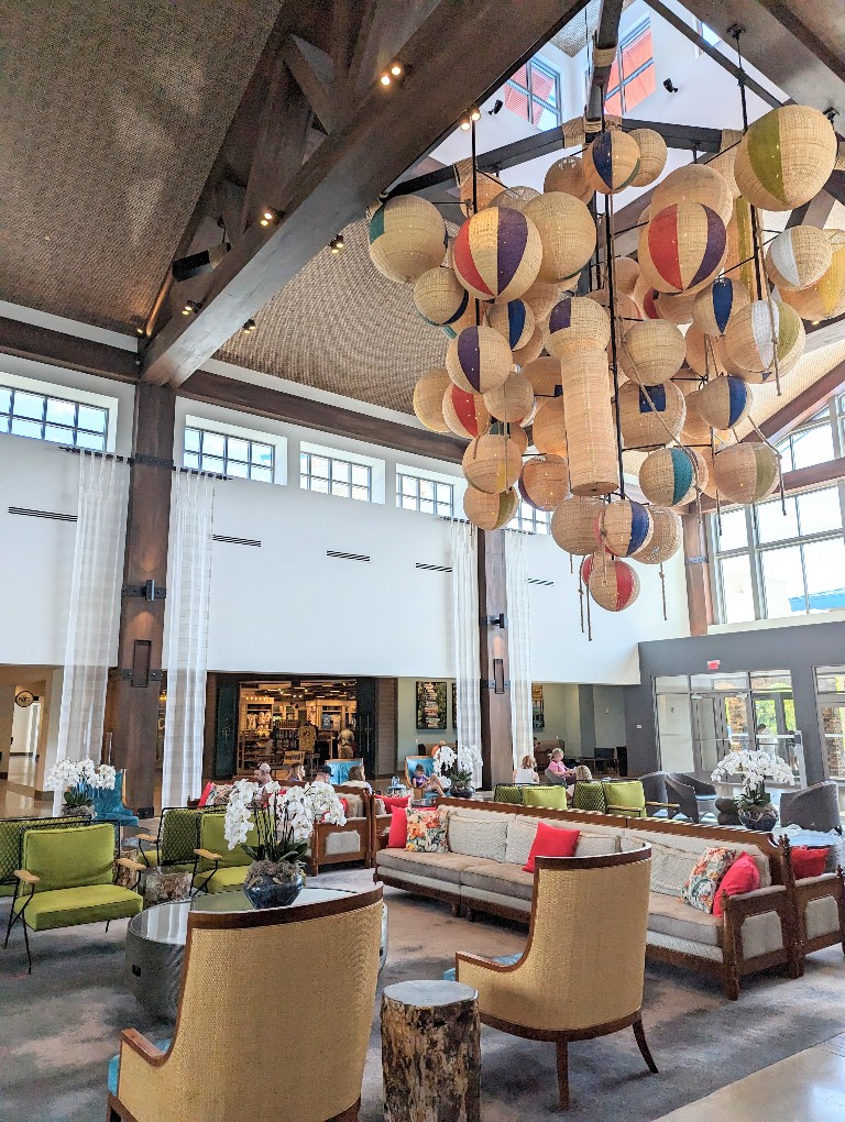 A large chandelier made to look like beach balls hangs above the warm neutral and bright tropical Sapphire Falls Universal Orlando lobby