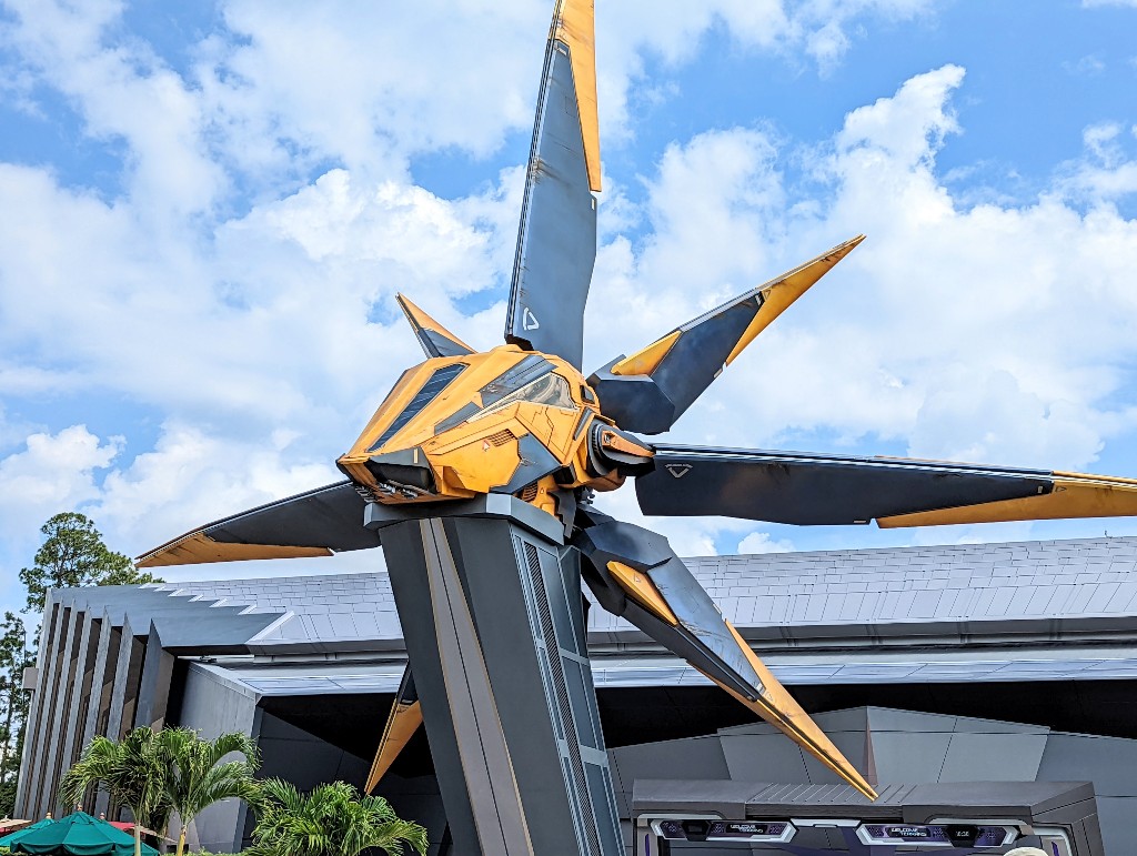 A bright yellow NOVA starcruiser sits in front of the Guardians of the Galaxy: Cosmic Rewind Lightning Lane and Virtual Queue entrance