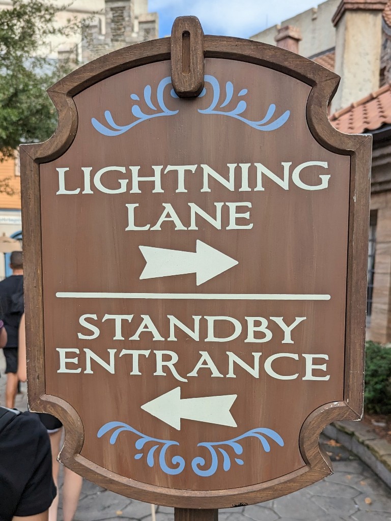 A wooden sign indicates which line guests enter for Lightning Lane and standby