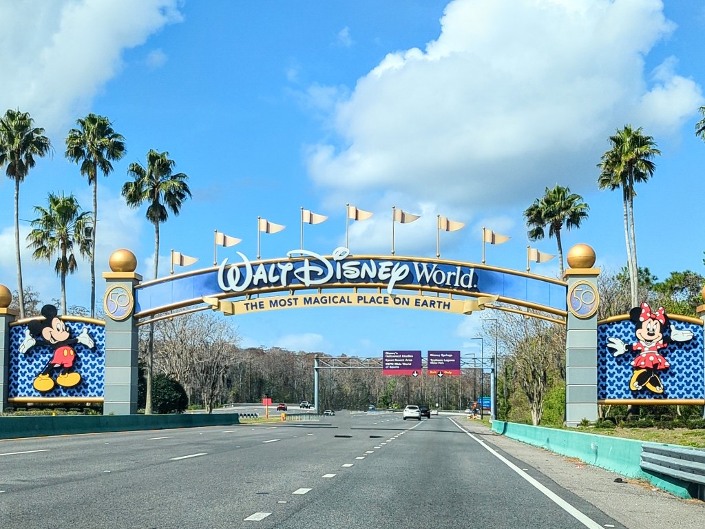 Bright blue skies and puffy white clouds frame the Walt Disney World entrance sign