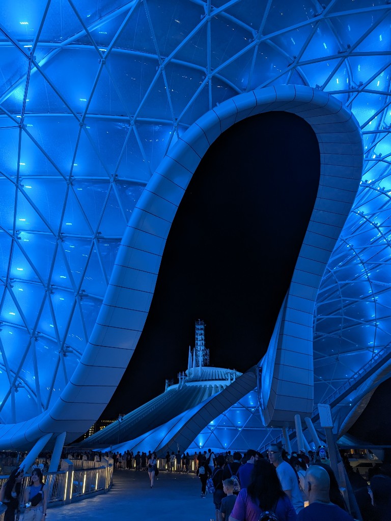 Cool blue lights illuminate the Tron Lightcycle Run canopy and frame Space Mountain in the background