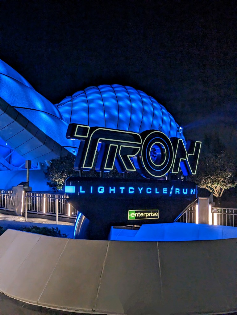 Tron Lightcycle Run sign illuminated in blue with the blue lighted canopy behind
