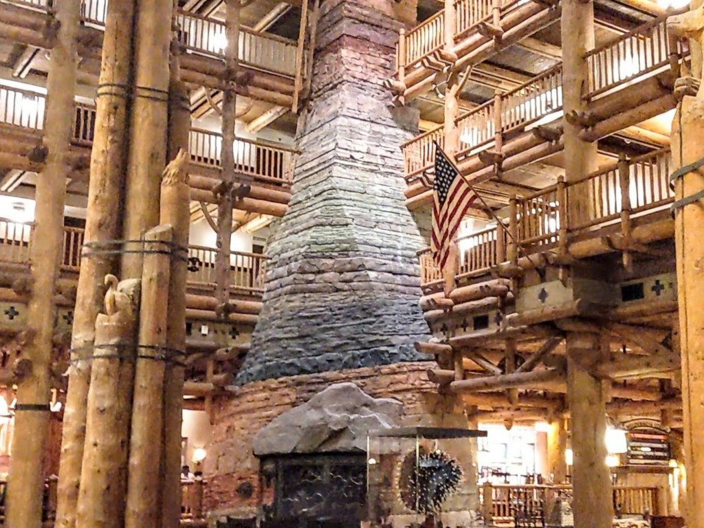 A multi-story stone fireplace and rustic log decor welcome guests into Disney's Wilderness Resort lobby