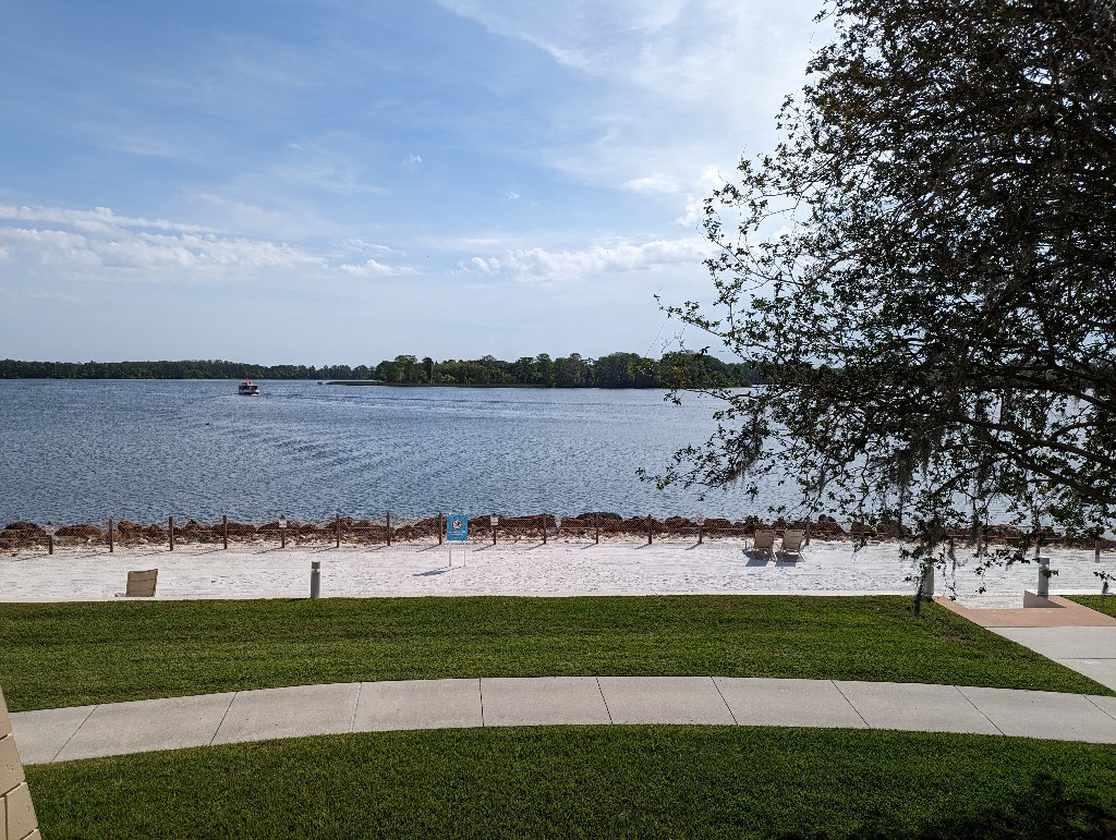 A thin section of beach with blue skies above the blue water of Bay Lake visible from a Disney's Contemporary Garden Wing room