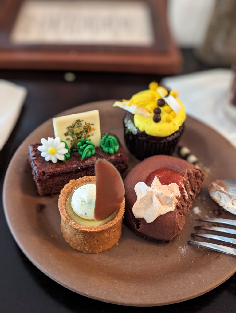 An assortment of mini cupcakes, tarts, brownies, and an incredible vegan chocolate mousse fill a dessert plate
