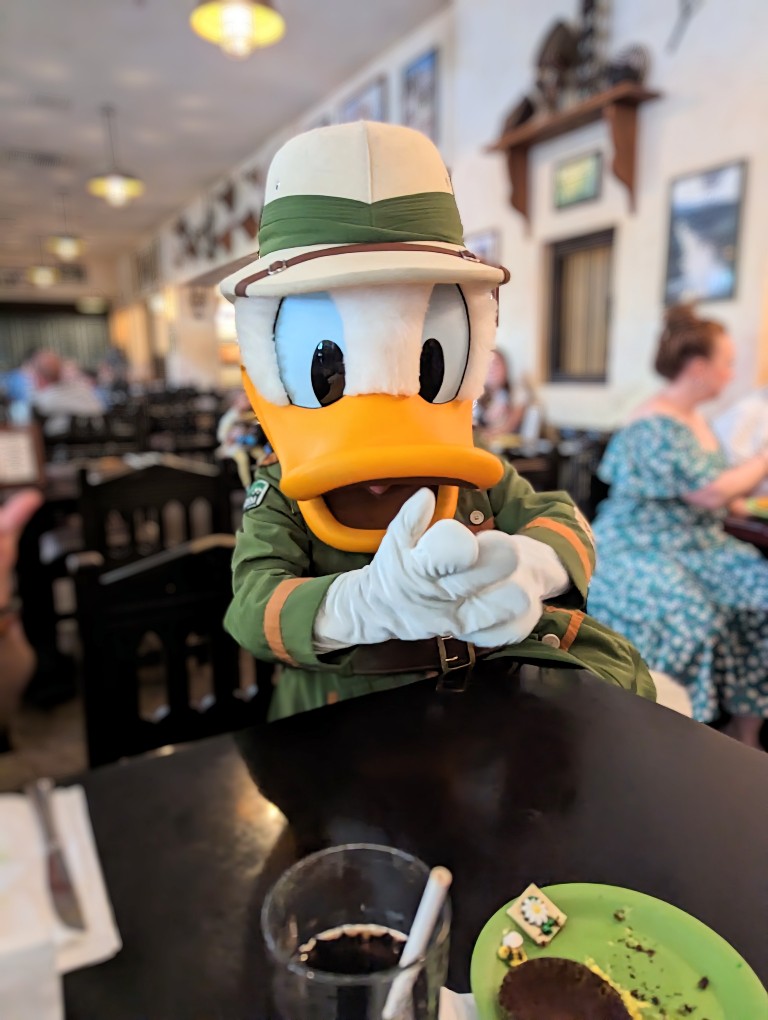 Donald Duck in safari gear sits at our table to discuss important things at a Tusker House character meal