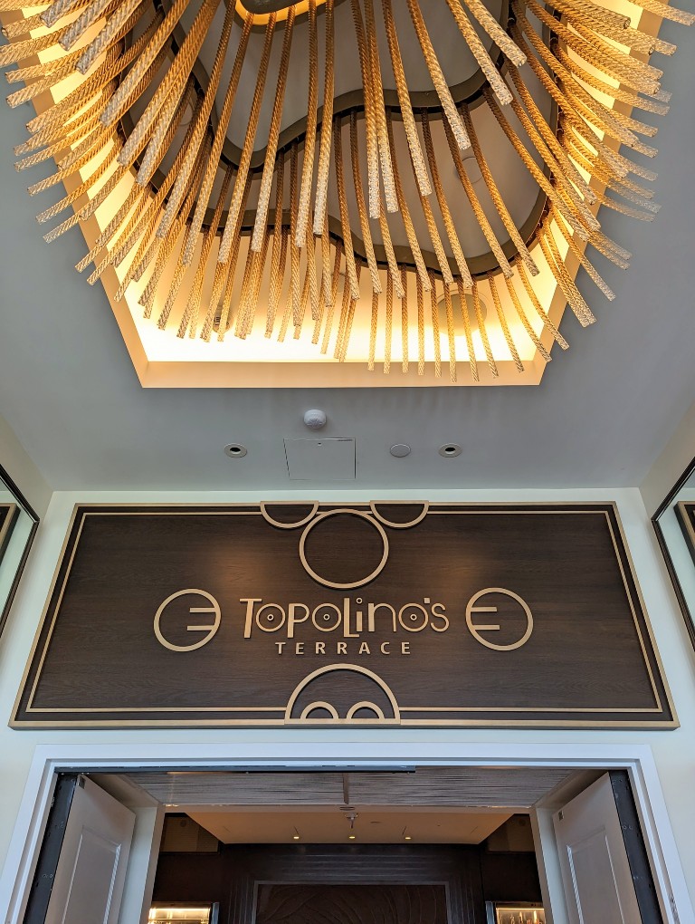 A golden chandelier of sparkling individual glass ribbons is a striking sight when entering Topolino's Terrace
