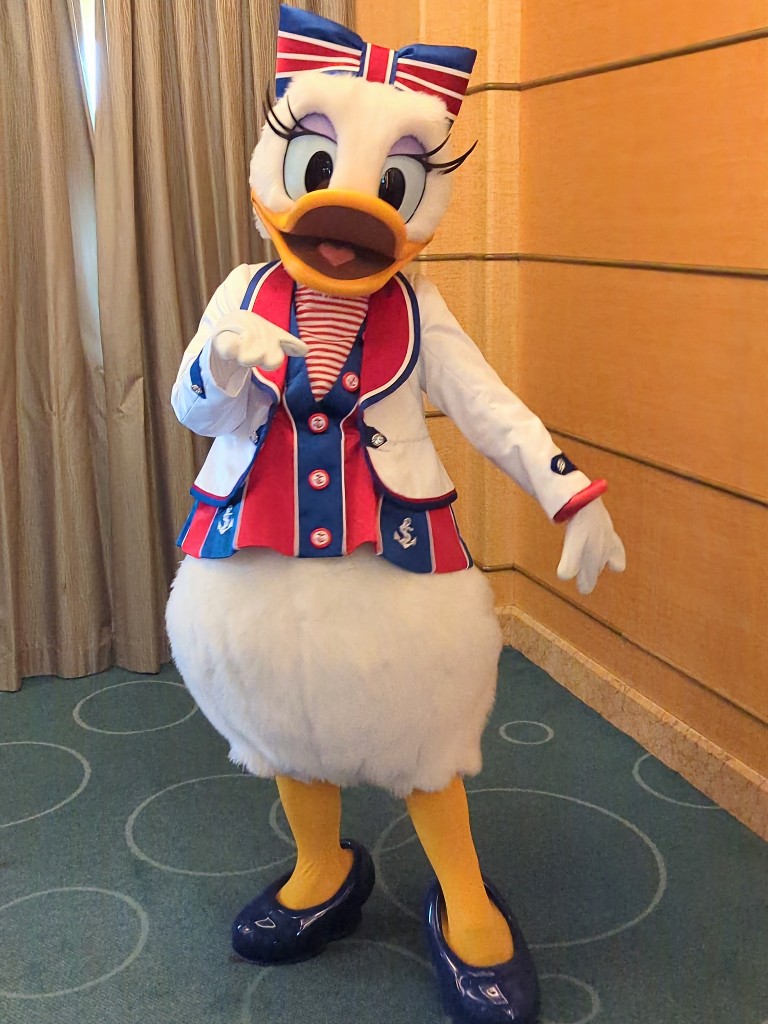 Daisy strikes a pose in her red, white, and blue striped outfit with matching bow during a Disney Cruise Line character meet and greet.