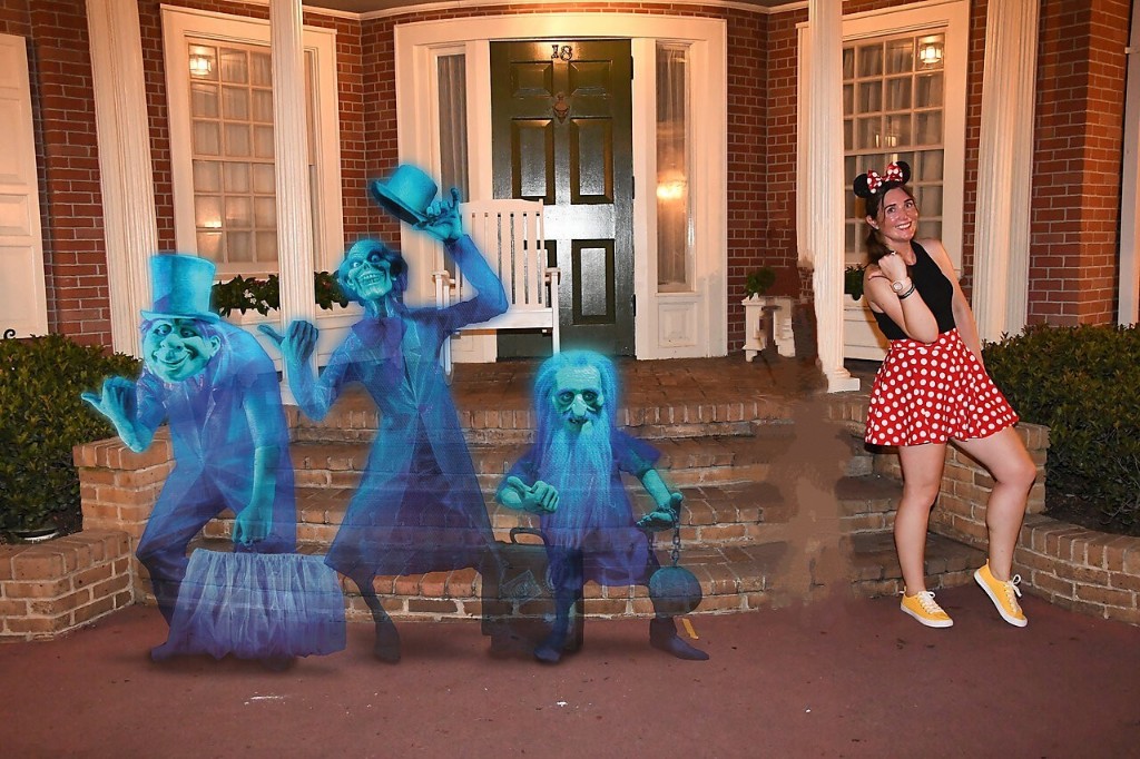 A woman poses with the Haunted Mansion hitchhiking ghosts during Mickey's Not So Scary Halloween Party