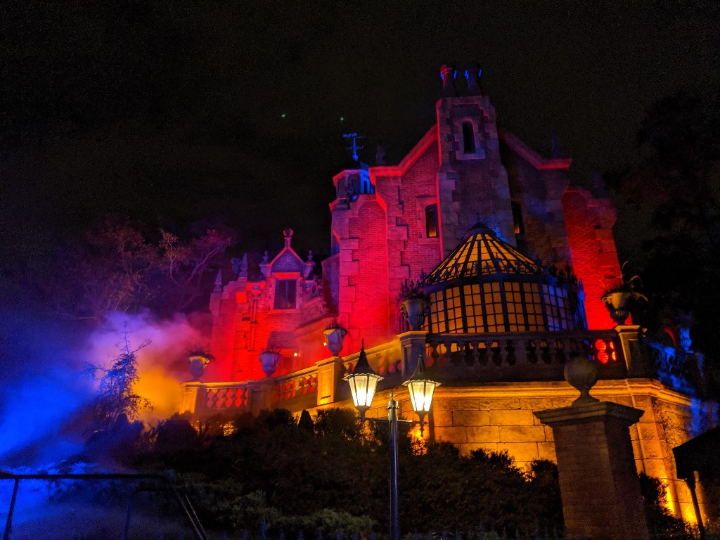 Orange, red, and purple lights bathe the Haunted Mansion in a creepy glow during Mickey's Not So Scary Halloween Party