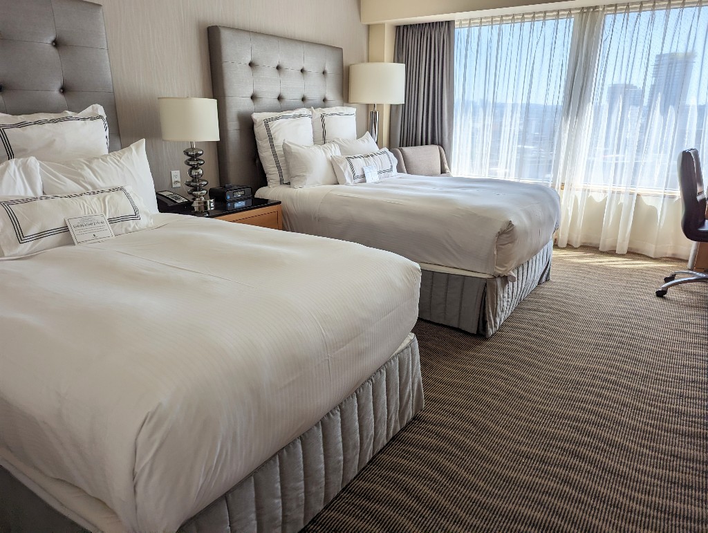 Two beds with upholstered gray headboards and simple white linens at Pan Pacific Vancouver at Canada Place