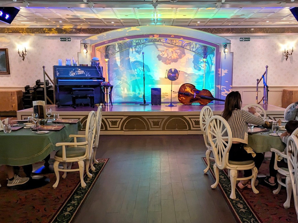 A stage with bass, piano, and microphone wait expectantly for performers at Tiana's Place on Disney Wonder