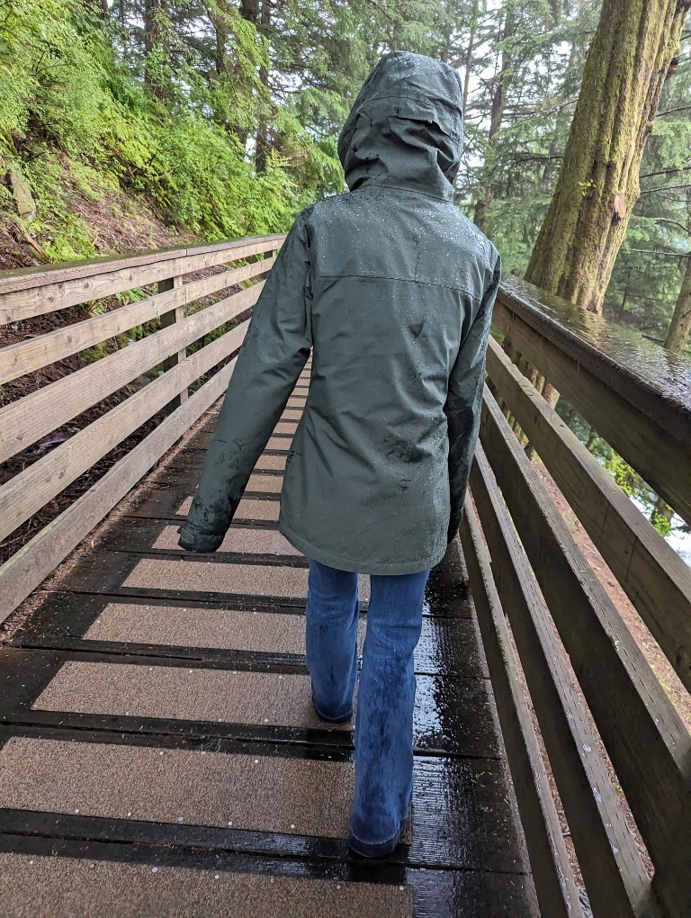 A girl walks in the rain using her raincoat as protection from the elements during a Disney Alaska cruise