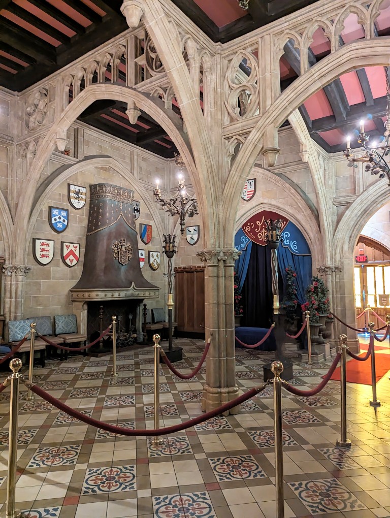 Stone arches, coats of arms, and a velvet photo background bring a castle-like feeling to Cinderella's Royal Table lobby