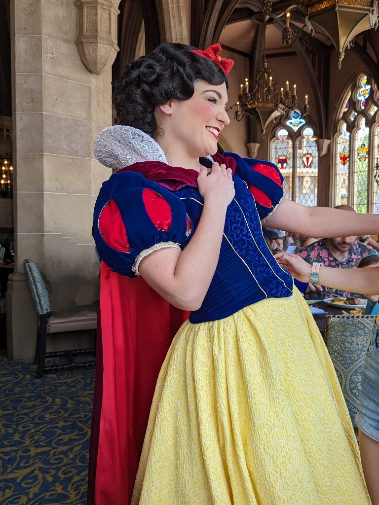 Snow White smiles widely as the approaches a table at Cinderella's Royal Table