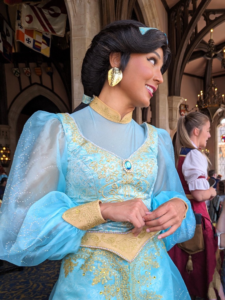 Jasmine smiles warmly in her gorgeous teal outfit and hammered gold earrings as she chats during our princess meal