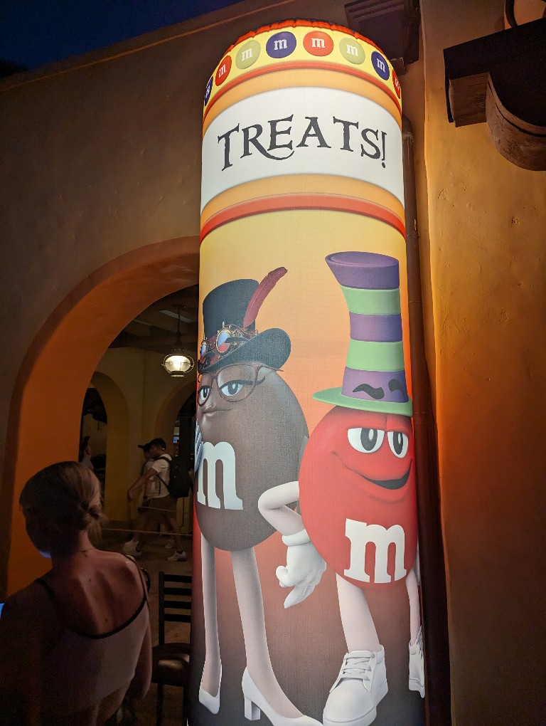A large, lighted inflatable "treat" sign indicates trick or treating spots during Mickey's Not So Scary Halloween Party