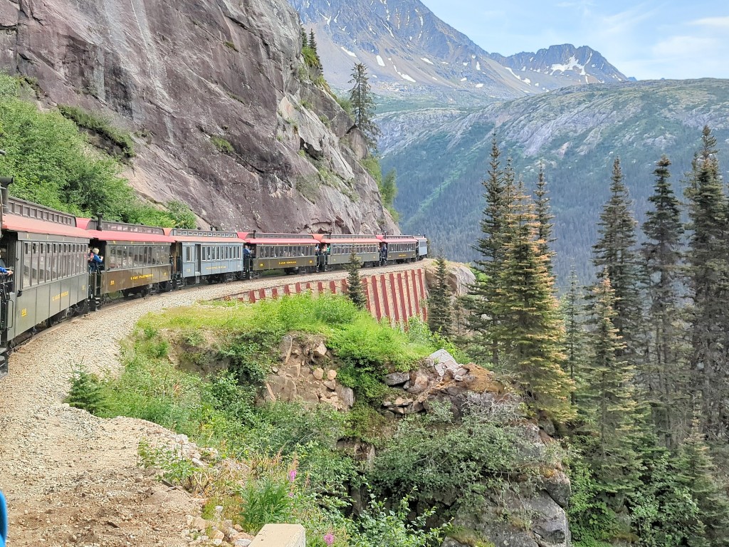The White Pass Railway train curves around the mountain on a cliffside track on one of our favorite Disney Alaska cruise excursions