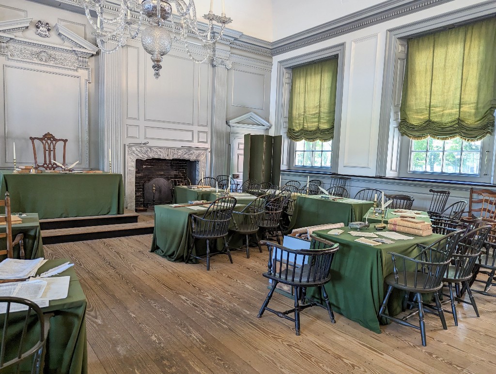 Independence Hall meeting room with period appropriate furniture draped in green tablecloths is where both the US Constitution and Declaration of Independence were debated and signed
