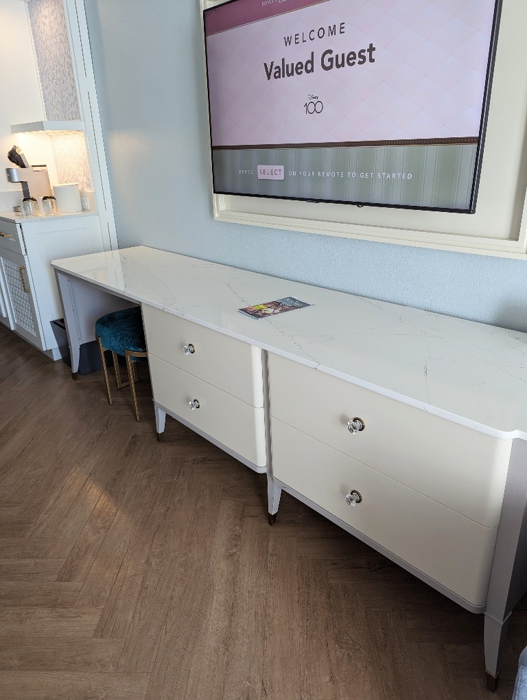 A long desk and dresser combination under the mounted TV in a Grand Floridian Resort room