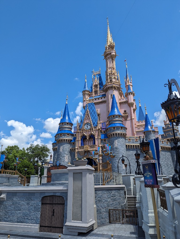 Disney World's Cinderella Castle with a bright blue sky and a handful of fluffy white clouds behind