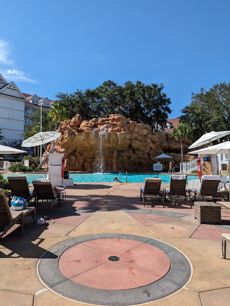 A waterfall and waterslide at Beach Pool framed by cabanas and loungers