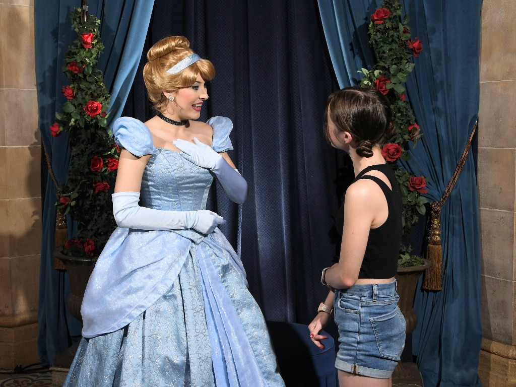 A girl listens closely as Cinderella smiles and chats with her at Cinderella's Royal Table