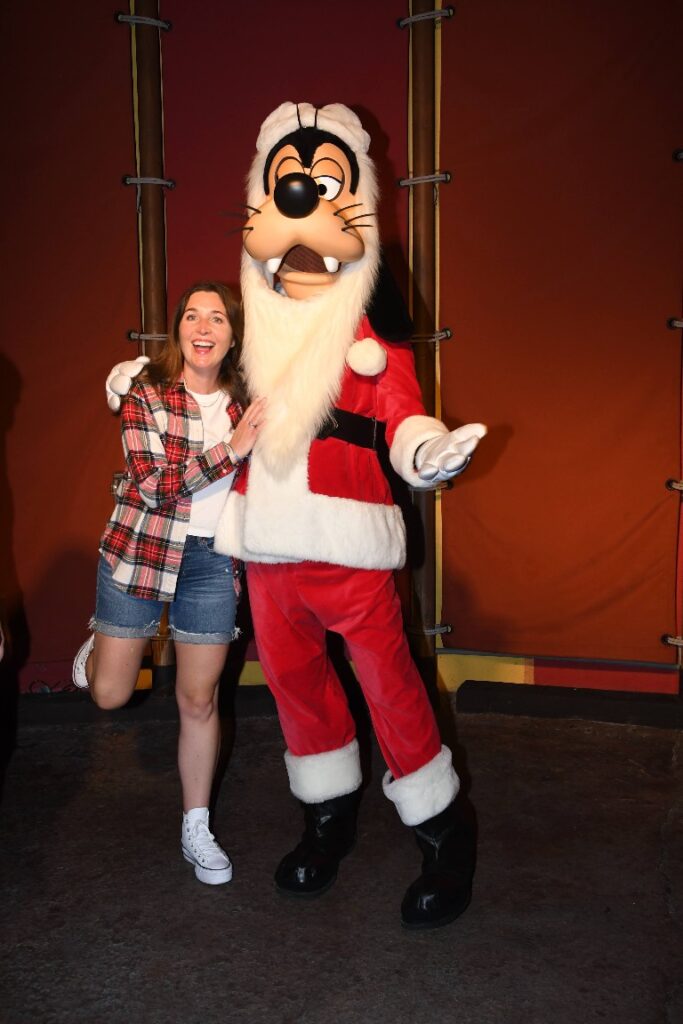 A woman smiles widely with Santa Goofy at Mickey's Very Merry Christmas Party