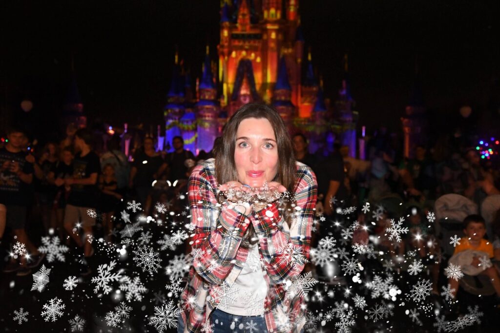 A woman blows snowflakes into the air in a Mickey's Very Merry Christmas Party PhotoPass magic shot