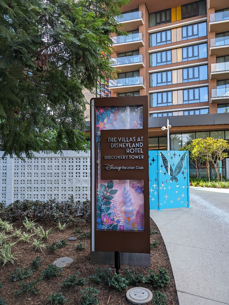 The Villas at Disneyland Hotel Discovery Tower sign in front of the tower with a trail of pixie dust leading to the entrance