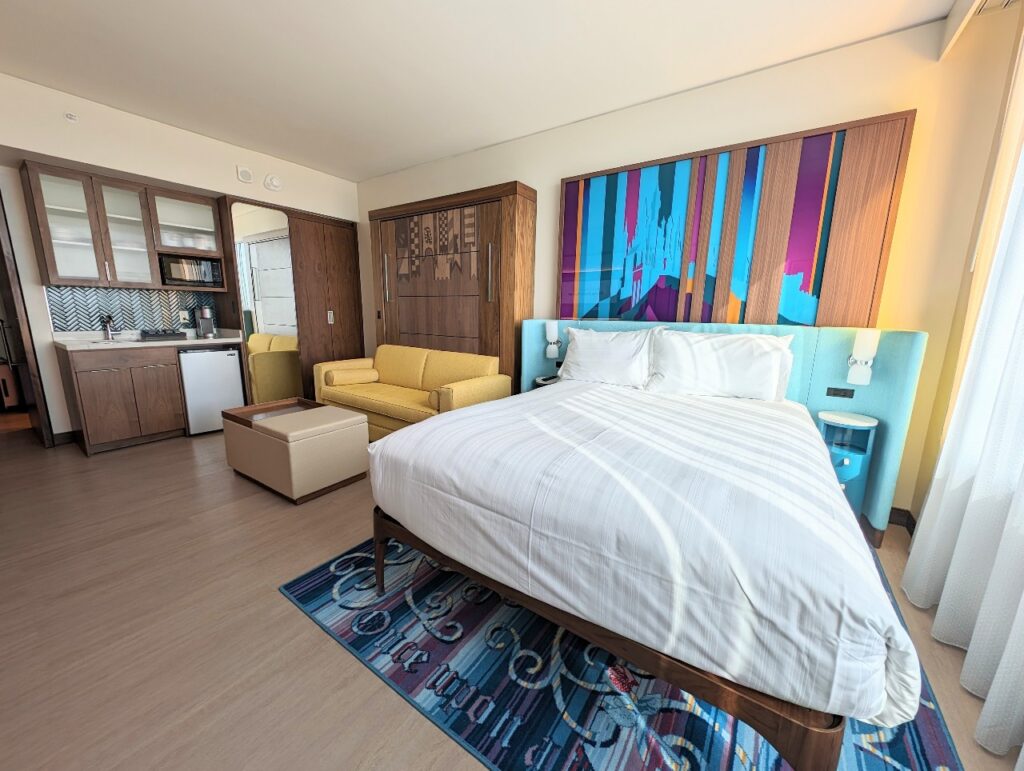 A fisheyed picture of the Villas at Disneyland Hotel Deluxe Studio Villa layout with kitchenette, bed, and couch which transforms into a Murphy bed