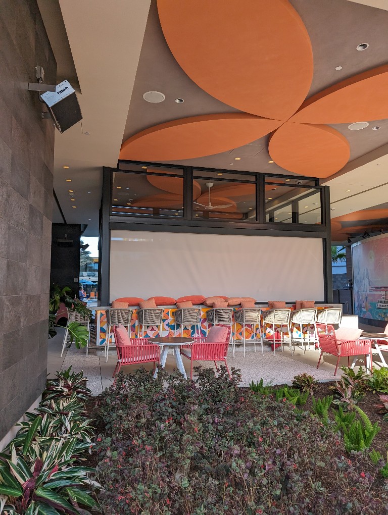 The new Palm Breeze Bar with shades drawn and bright chairs surrounding the bar next to Disneyland Hotel Villa Discovery Tower