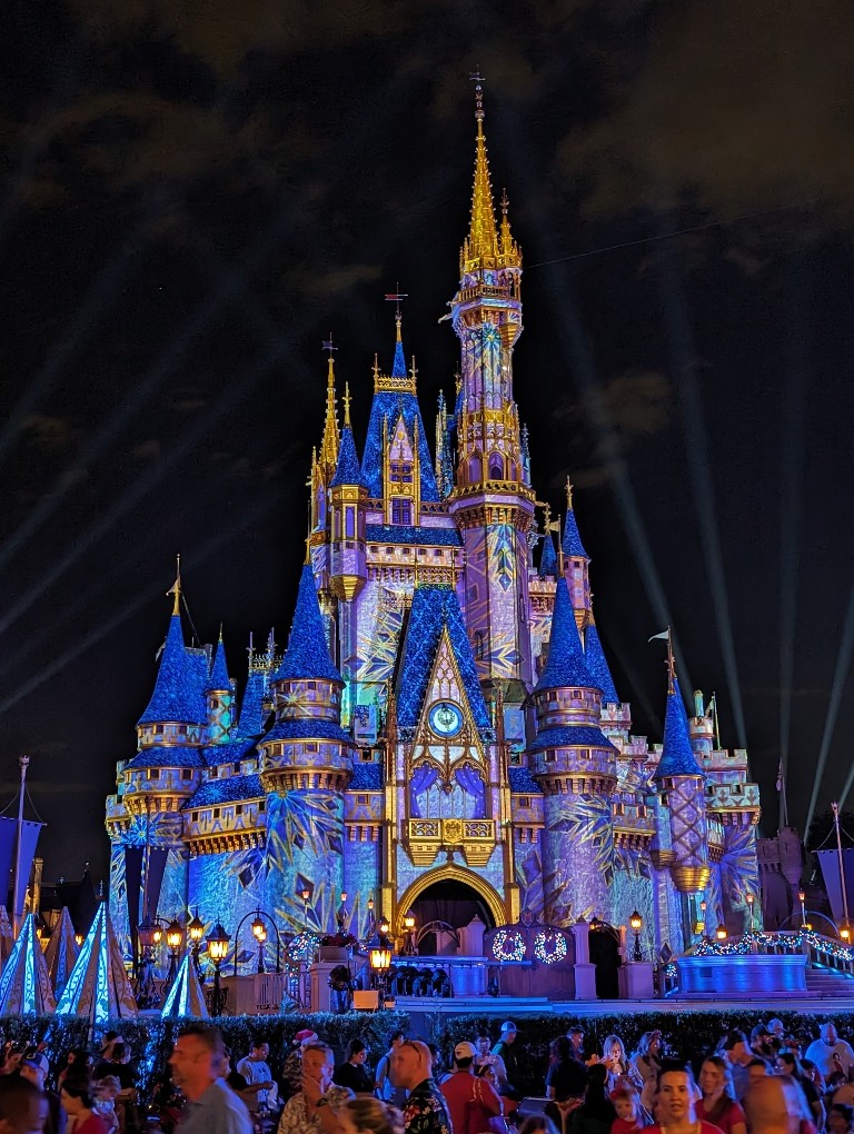 Elsa covers Cinderella Castle in blue and purple icicles during Frozen Holiday Surprise