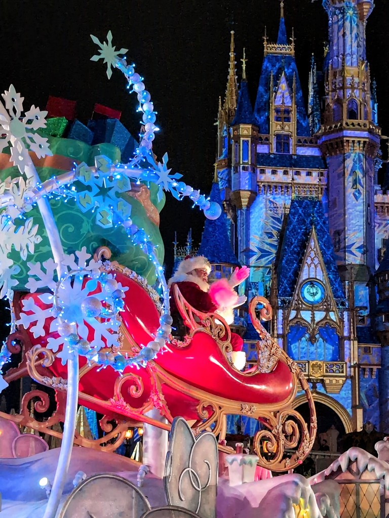 Santa sits high on a float waving to guests in front of Cinderella Castle during the Mickey's Very Merry Christmas Party parade