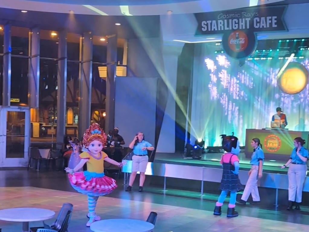 Fancy Nancy and Vampirina dance to a DJ inside Cosmic Ray's during Mickey's Very Merry Christmas Party