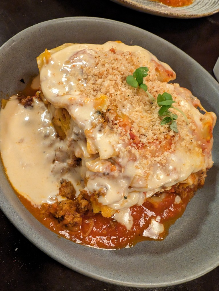 A large piece of lasagna covered in melted cheese and toasted breadcrumbs at Trattoria Al Forno at Disney's Boardwalk Inn