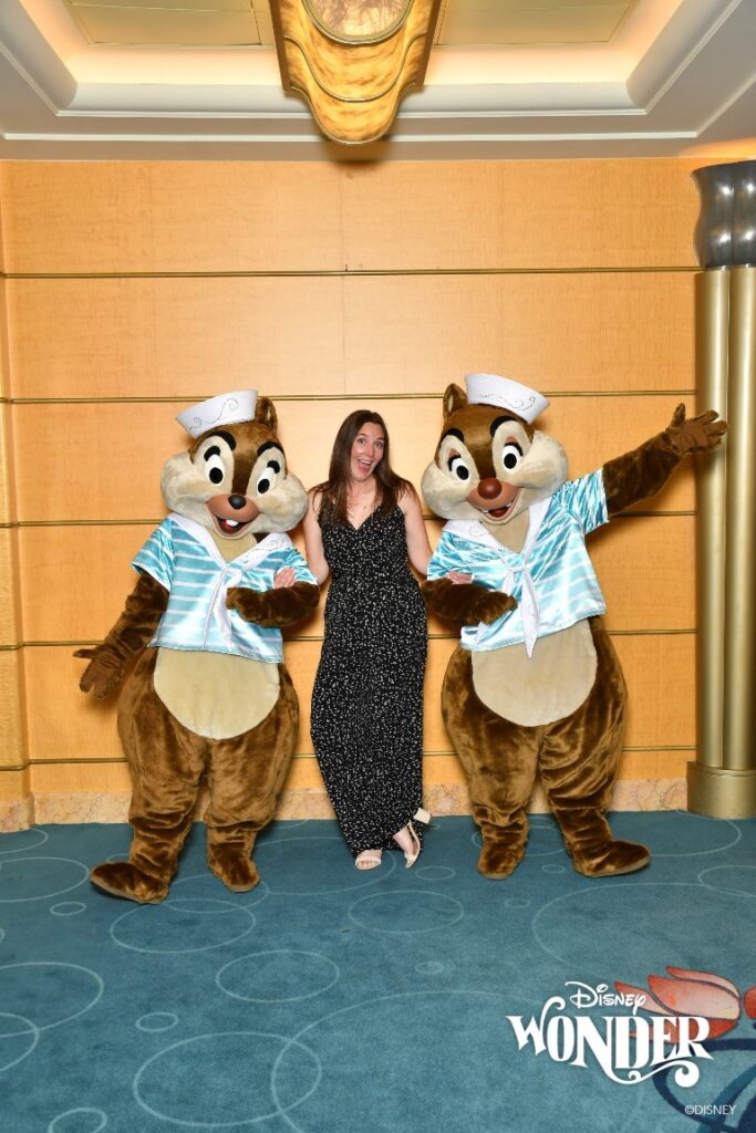 A woman poses with Chip and Dale wearing a dressy black jumpsuit for Disney Alaska Cruise semi-formal night
