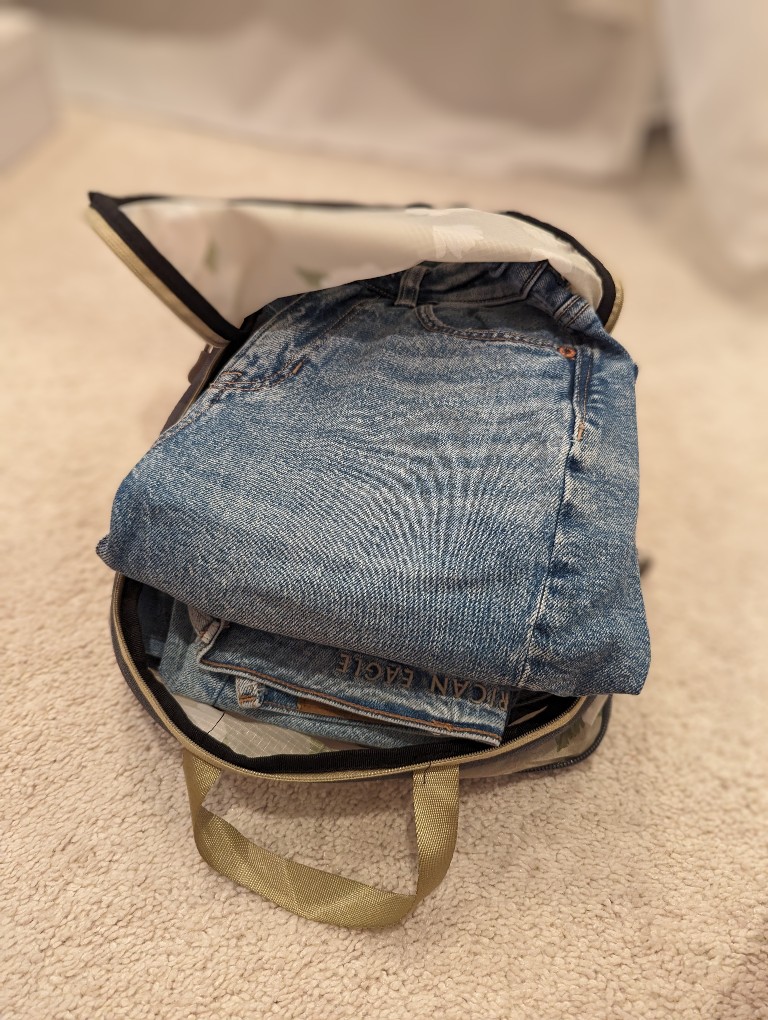 Jeans sit inside a packing cube waiting to be zippered closed