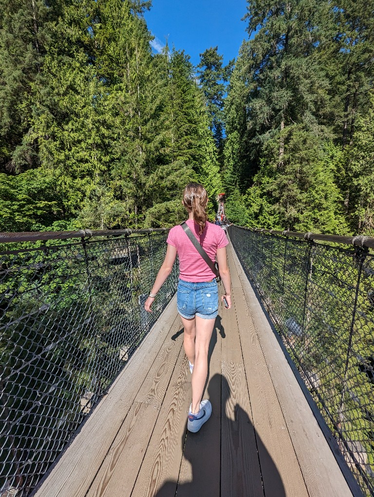 A girl wears shorts and a t-shirt crossing the Capilano Suspension Bridge in Vancouver before taking a Disney Alaska Cruise