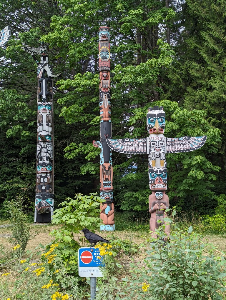 Three totem poles in various carving styles and colors grouped together in Vancouver's Stanley Park