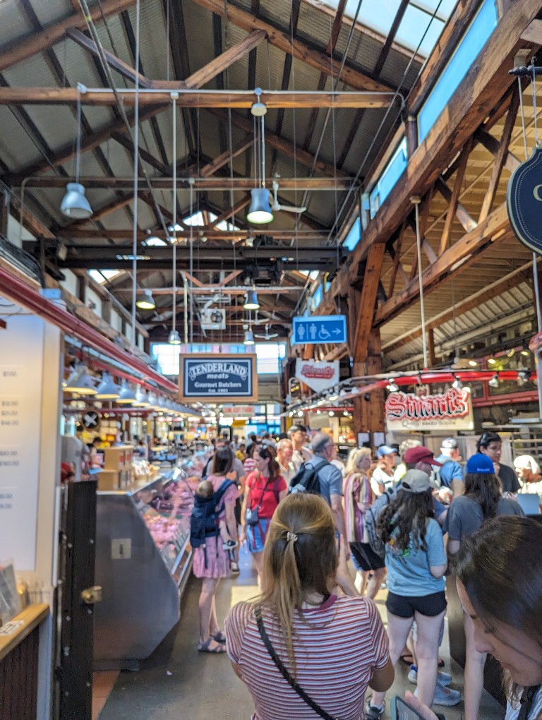 Various food booths are surrounded by visitors choosing delicious items at Granville Public Market in Vancouver