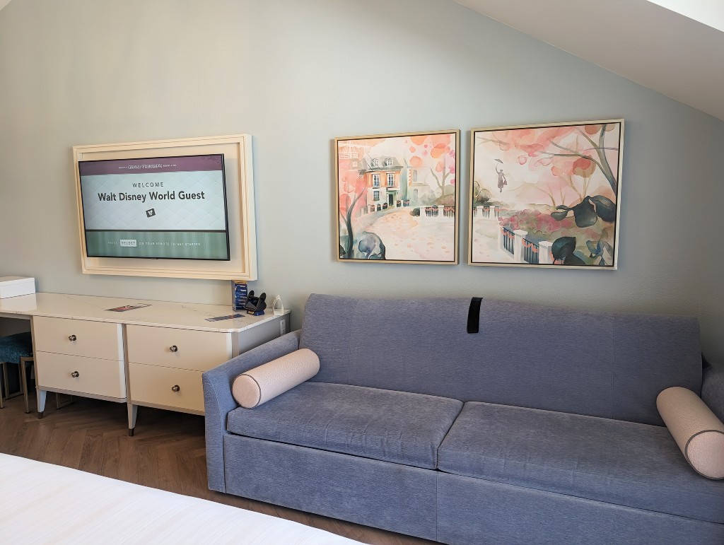 Soft pastel watercolors representing scenes from Mary Poppins hang above a couch that transforms into a single day bed